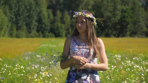 Girl is walking along the field of flax. Young girl going away in golden field.