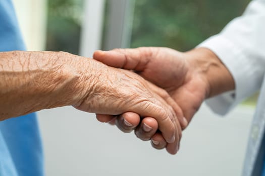 Caregiver holding hands Asian elderly woman patient with love, care, encourage and empathy at nursing hospital, healthy strong medical concept.