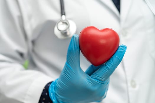 Doctor holding a red heart in hospital ward, healthy strong medical concept.