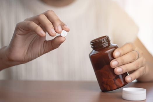 Hand taking medicine from a brown bottle for medical and healthcare concept.