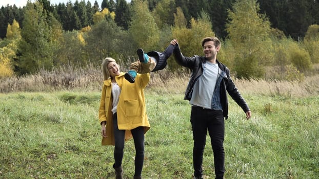 Young family walking in the autumn park with his son, holding his hand.Happy mother, father and little girl walking in autumn park and having fun. Happy young family spending time together outside in green nature.