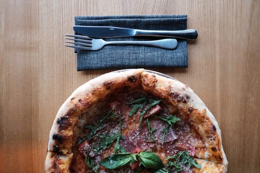 Delicious Prosciutto Pizza with Tomatoes, Cheese, and Arugula on Wooden Table