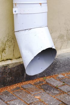 Sewer pipe near the wall of the building on the sidewalk
