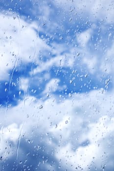 Abstract background of rain drops on glass on a background of blue bright sky