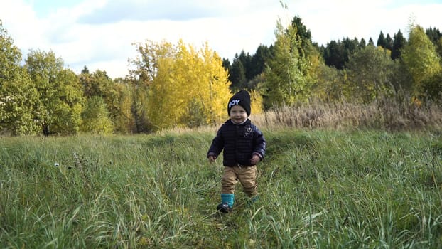 Little boy walks in the park in autumn day. Little boy running on the countryside road.Kid in the park.