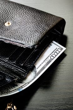 One hundred dollar bill in a black wallet