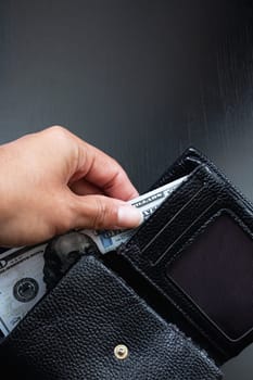 One hundred dollar bill in black wallet in hand, copy space