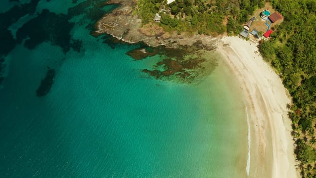 Beautiful tropical beach in cove with blue lagoon and turquoise water. Seascape with sea, sand, palm trees. Nagtabon, Palawan, Philippines. Summer and travel vacation concept