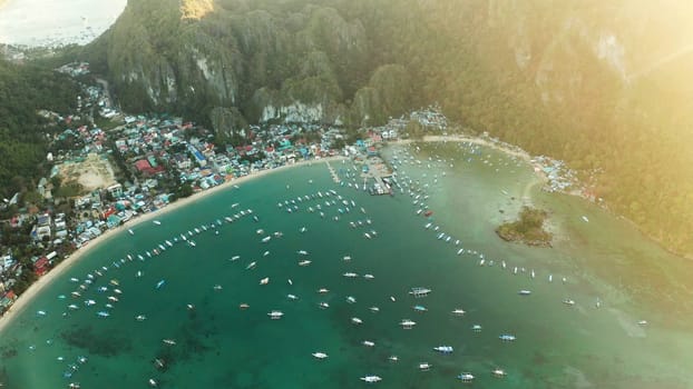 Many boats in the turquoise lagoon at sunset. Seascape with blue bay and boats view from above. El nido, Palawan, Philippines. traditional Filipino wooden outrigger boat called a banca. Summer and travel vacation concept