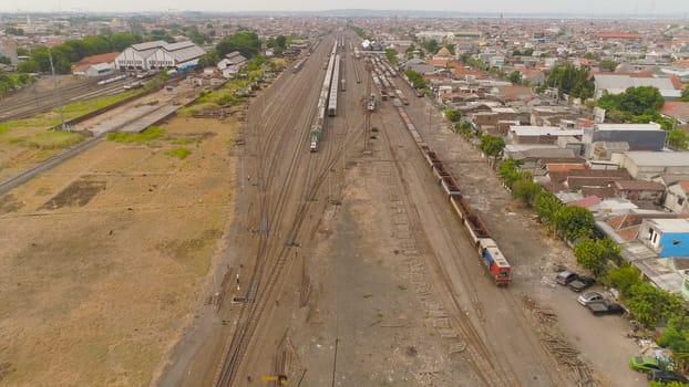 freight train with cisterns and containers on railway station Surabaya Indonesia. Wagons with goods on railroad. Heavy industry. railway station in an asian city among buildings.