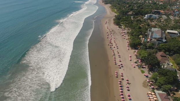 Aerial view sand beach with resting people, hotels and tourists, sun umbrellas, Bali, Kuta. surfers on water surface. Seascape, beach, ocean, sky sea Travel concept