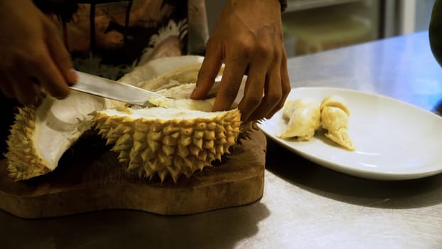 hand peeling and cuts durian fruit. caucasian man peeling durian in kitchen room