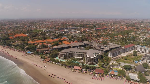 Aerial view sand beach with resting people, hotels and tourists, sun umbrellas, Bali, Kuta. surfers on water surface. Seascape, beach, ocean, sky sea Travel concept
