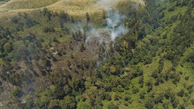 aerial view forest fire smoke on slopes hills. wild fire in tropical forest, Java Indonesia. natural disaster fire in Southeast Asia