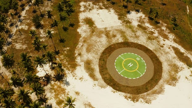 Helipad among the palm trees on a tropical island from above. Helicopter landing site. Bugsuk island, Balabac, Palawan