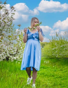 Pregnant woman in the garden of flowering apple trees. Selective focus. Nature.
