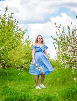 Pregnant woman in the garden of flowering apple trees. Selective focus. Nature.