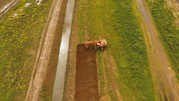Excavator is digging an irrigation canal. Aerial view:Excavator digging a deep trench.excavator is digging an drainage canal in the agricultural field.