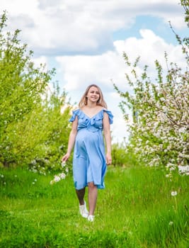 Pregnant woman in the garden of flowering apple trees. Selective focus. Nature.