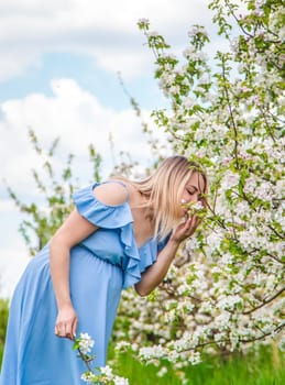 Pregnant woman in the garden of flowering apple trees. Selective focus. Nature.