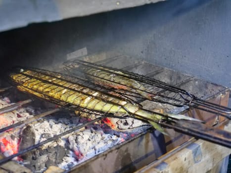 Fresh fish put on the fire, for cooking grill. Fish grilled on grid.