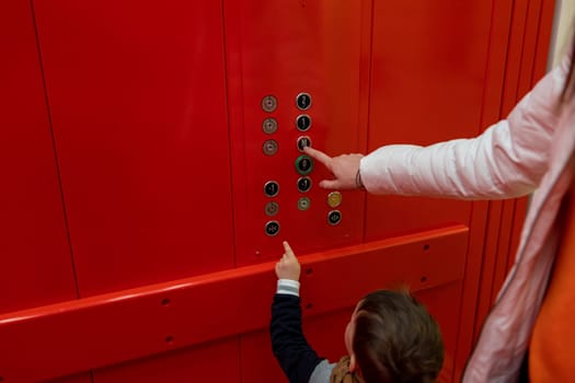 small boy pressing button in red elevator. High quality photo