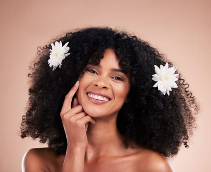 Portrait, hair care and black woman with flowers, smile and texture with girl on brown studio background. Face, African American female and lady with plants, florals and confident with afro or volume.