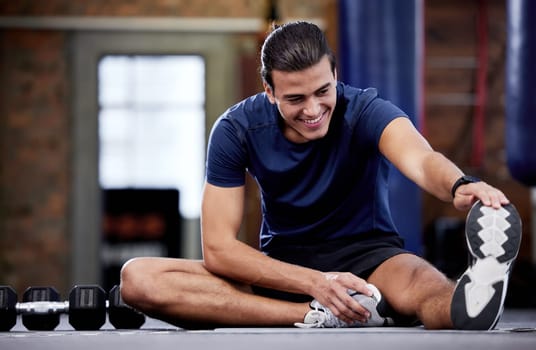 Fitness, man and stretching legs in gym for health, mobility and flexibility. Sports, wellness and happy male warm up or preparing for training, exercise or workout in fitness center for healthy body.