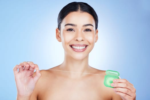 Face, floss teeth and dental with woman, hygiene and beauty with grooming and container on blue background. Hands, string and oral care product, healthy gums with fresh breath, health and portrait.