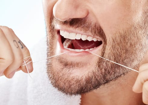 Dental, hygiene and man flossing his teeth in a studio for oral care, grooming or health. Wellness, healthy and closeup of male model doing fresh, clean and natural mouth routine by white background