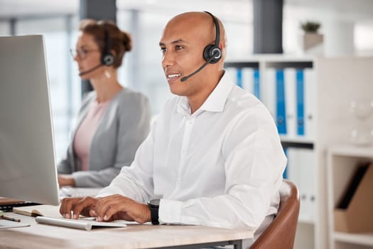 Call center, customer service and support with a man consultant working on a computer in his sales office. Retail, ecommerce and communication with a male consulting using a headset for help.