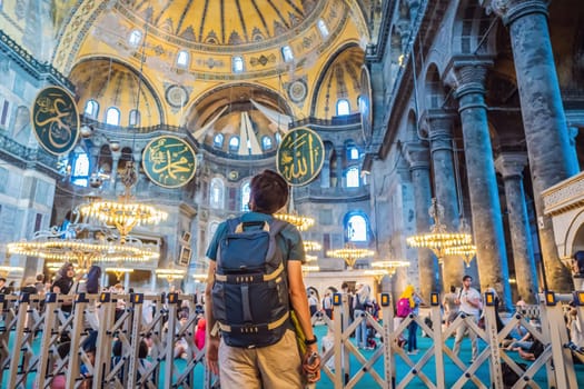 INSCRIPTION - denoting the names of Allah, the Prophet Muhammad, as well as the first 4 caliphs Man tourist enjoying Hagia Sofia, Ayasofya interior in Istanbul, Turkey, Byzantine architecture, city landmark and architectural world wonder. Turkiye.