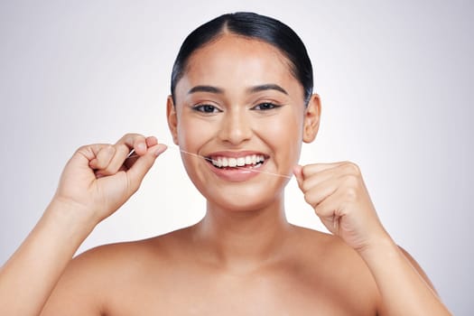 Happy woman, portrait and dental floss for clean teeth, hygiene or healthcare against a white studio background. Female person or model smiling in flossing, tooth cleaning or oral, gum and mouth care.