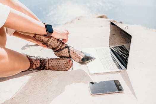 Happy girl doing yoga with laptop working at the beach. beautiful and calm business woman sitting with a laptop in a summer cafe in the lotus position meditating and relaxing. freelance girl remote work beach paradise