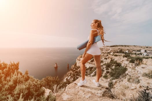 Middle aged well looking woman with black hair doing Pilates with the ring on the yoga mat near the sea on the pebble beach. Female fitness yoga concept. Healthy lifestyle, harmony and meditation.