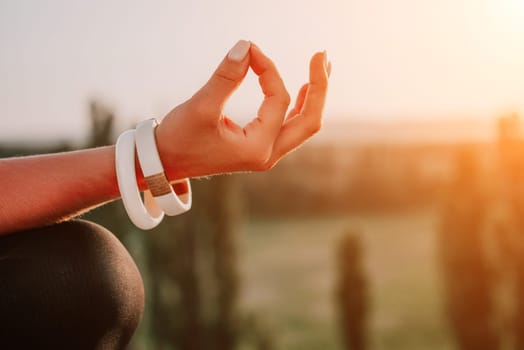 Well looking middle aged woman with long hair, fitness instructor in leggings and tops doing stretching and pilates on the rock near forest. Female fitness yoga routine concept. Healthy lifestyle.