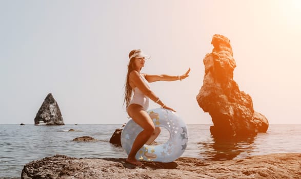 Woman summer sea. Happy woman swimming with inflatable donut on the beach in summer sunny day, surrounded by volcanic mountains. Summer vacation concept