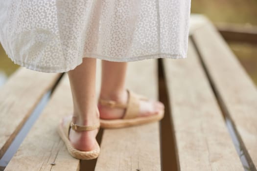 girl's legs in summer sandals on the pier in summer. High quality photo