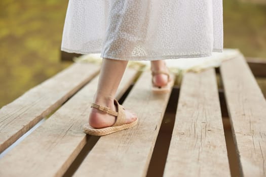 girl's legs in summer sandals on the pier in summer. High quality photo