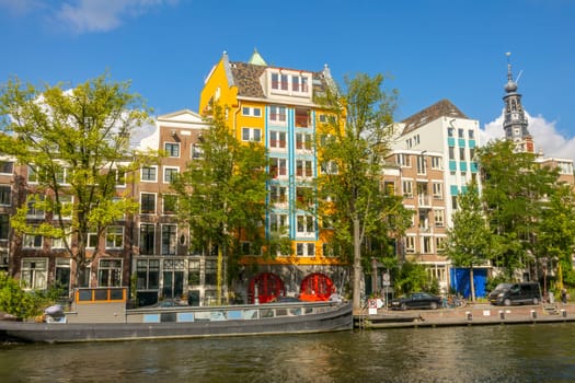 Netherlands. Sunny summer day on the Amsterdam Canal. Facades of typical Dutch buildings and residential barge at the pier