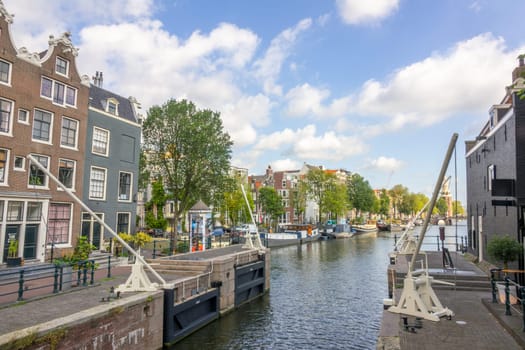 Netherlands. Old ship lock on the Amsterdam Canal. Typical Dutch houses and residential barges on the water