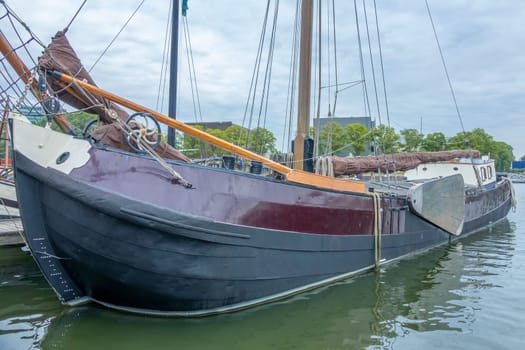 Netherlands. Cloudy day on the Amsterdam canal. Old cargo sailing ship at the pier