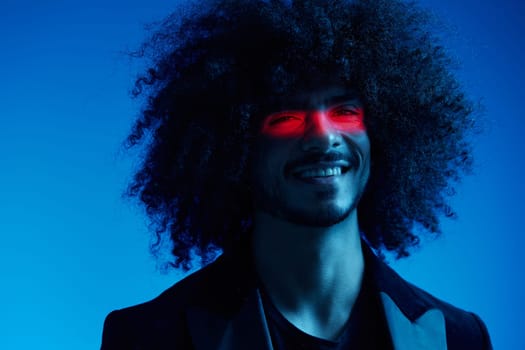 Fashion portrait of a man with curly hair on a blue background with a red stripe of light, multicolored light, trendy, modern concept. High quality photo