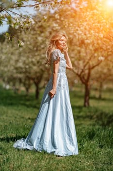 Portrait of a blonde in the park. Happy woman with long blond hair in a blue dress