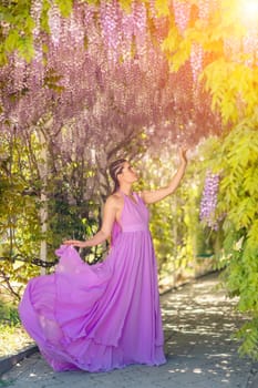 Woman wisteria lilac dress. Thoughtful happy mature woman in purple dress surrounded by chinese wisteria.