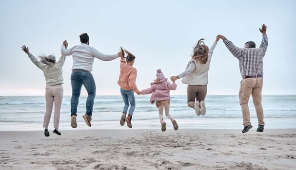 Family at the beach, adventure and jump, generations love and care while holding hands and fun by the ocean. Big family travel, parents with grandparents and children together and freedom at sea