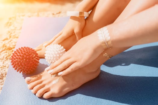 Middle aged well looking woman with black hair doing Pilates with the ring on the yoga mat near the sea on the pebble beach. Female fitness yoga concept. Healthy lifestyle, harmony and meditation.