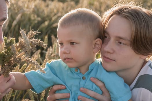 A little boy and his teenage brother are having fun walking in a field with ripe wheat. Grain for making bread. the concept of economic crisis and hunger