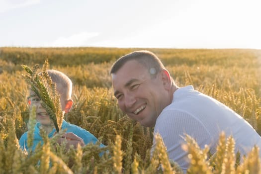 Dad and his little son are having fun walking in a field with ripe wheat. Grain for making bread. the concept of economic crisis and hunger