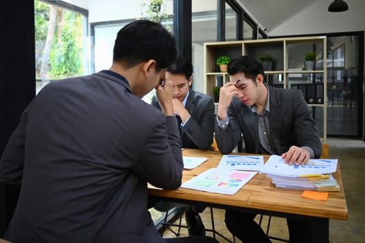 Exhausted business colleagues feel stressed with bad work result or paperwork statistics problem at meeting room.